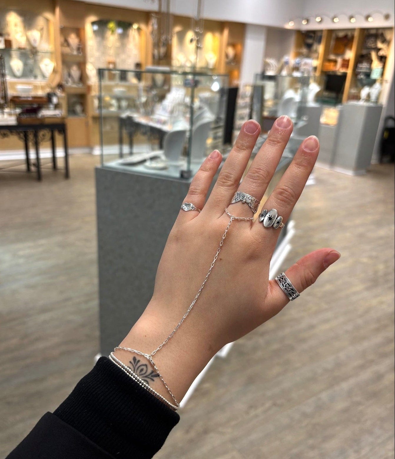 Hand wearing multiple rings with a blurred store interior background