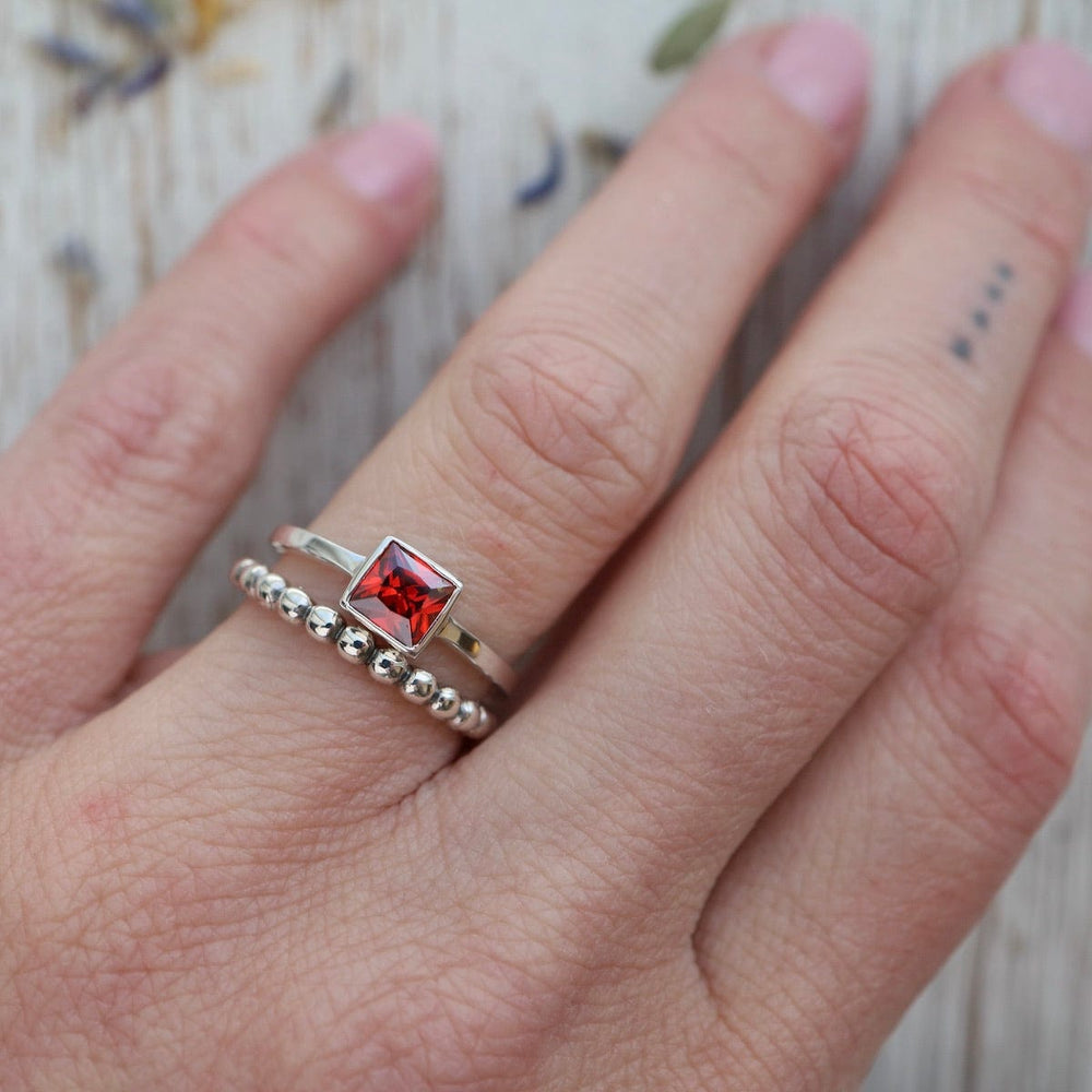 
                      
                        RNG Bezel Set Square Red CZ Silver Ring
                      
                    